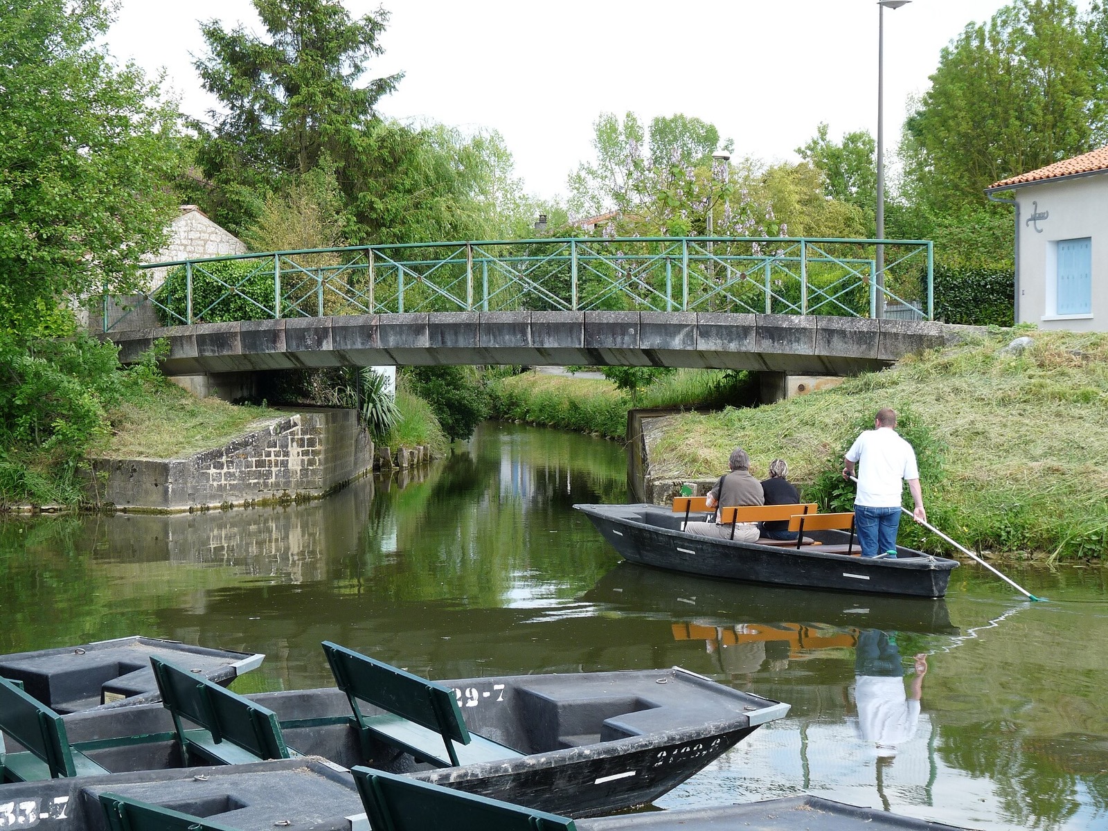 Promenade en barque plate sur un canal du marais poitevin &agrave; Coulon, sous une passerelle m&eacute;tallique